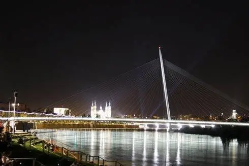 A orillas del Ebro, los visitantes contemplan una espectacular panor&aacute;mica de la Pasarela del Voluntariado. Al fondo, el Pilar no pierde su protagonismo y, con sus focos, parece saludar al cielo.
Por Gonzalo Baz&aacute;n y Pilar Artiaga