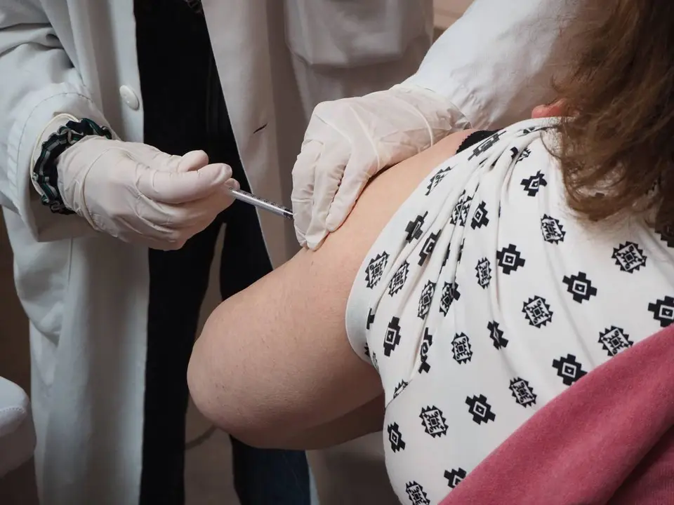 Un m&eacute;dico pone una vacuna en el brazo de una mujer