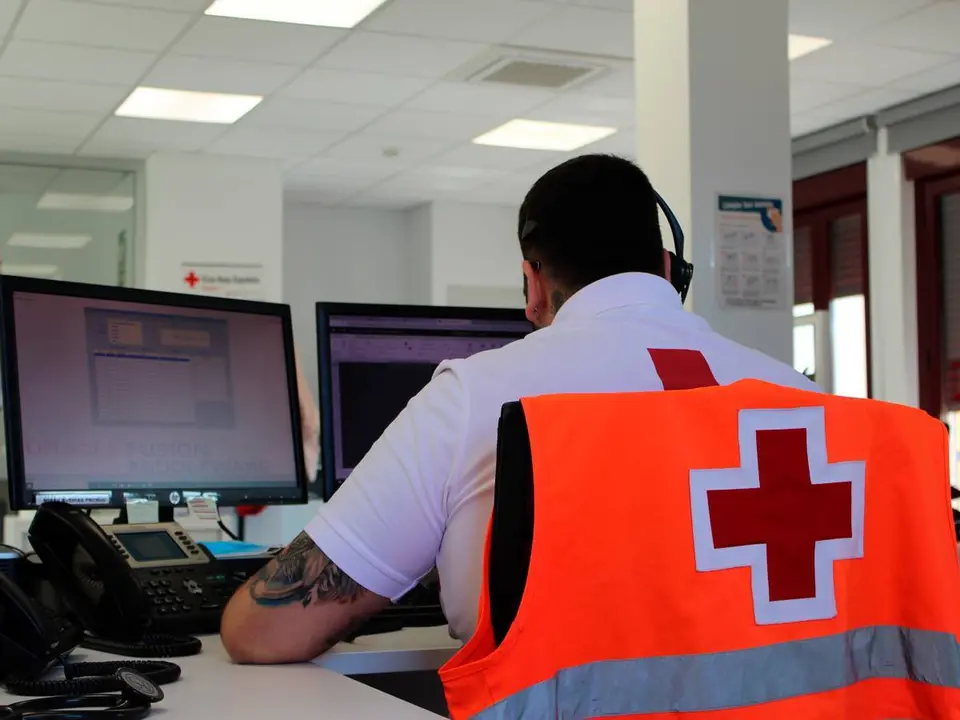 Un operario de la cruz roja trabaja con un ordenador en una oficina