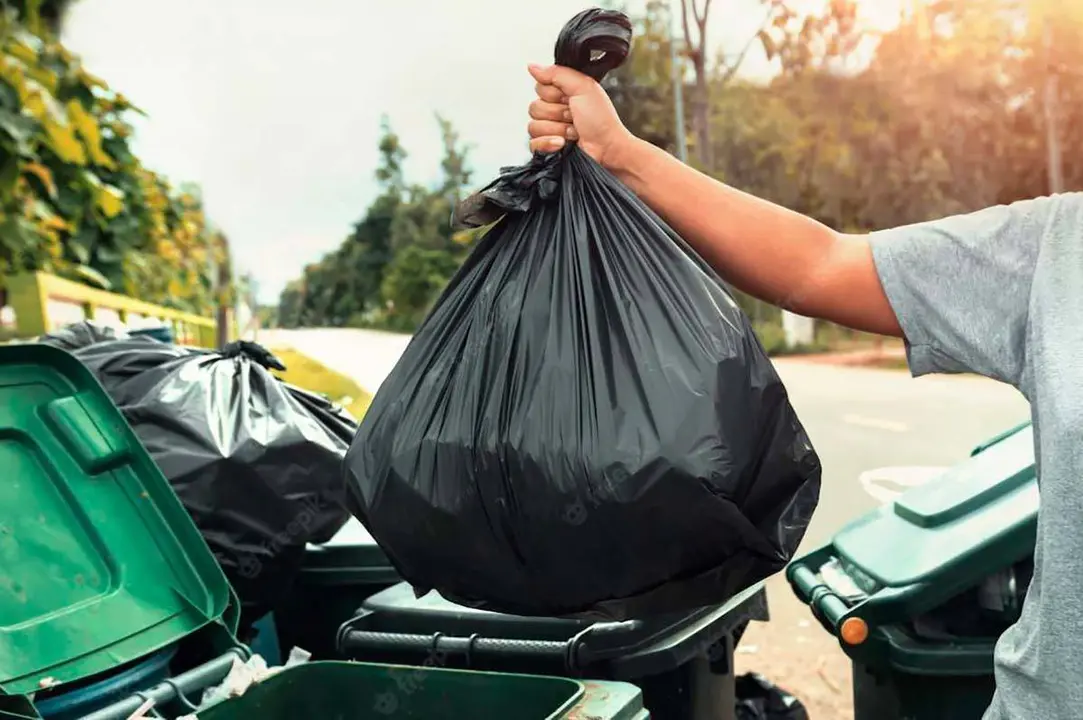 Una persona arroja una bolsa de basura a un contenedor