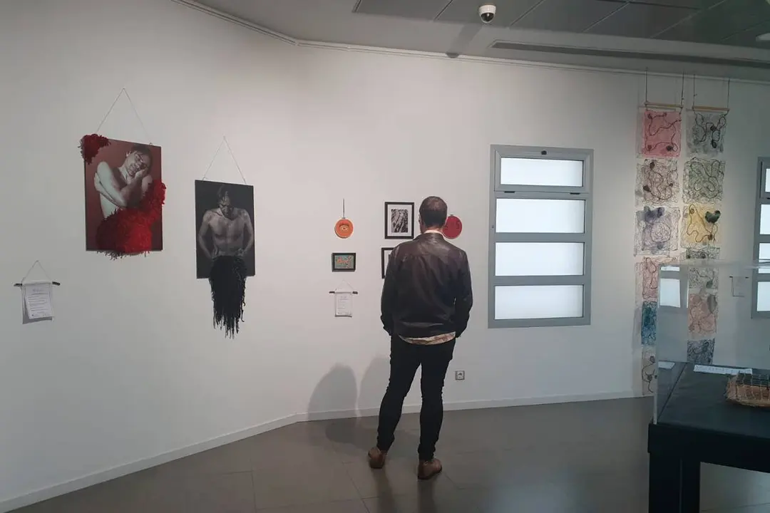 Un hombre viendo la exposici&oacute;n, varias piezas de arte textil en el fondo