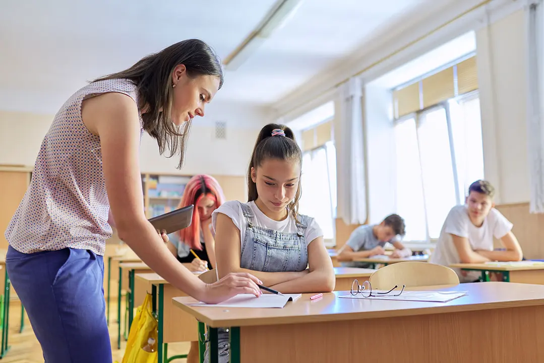 Profesora joven ense&ntilde;a lecci&oacute;n en clase de ni&ntilde;os adolescentes