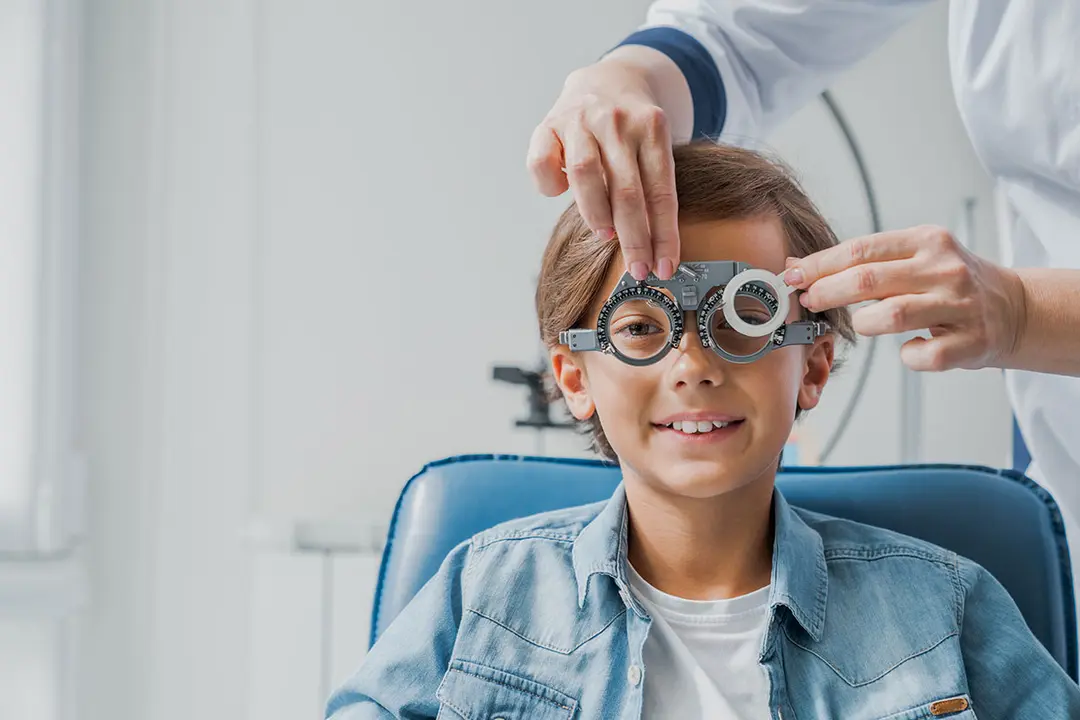 Ni&ntilde;o con gafas comprueba la visi&oacute;n ocular en el oftalm&oacute;logo pedi&aacute;trico