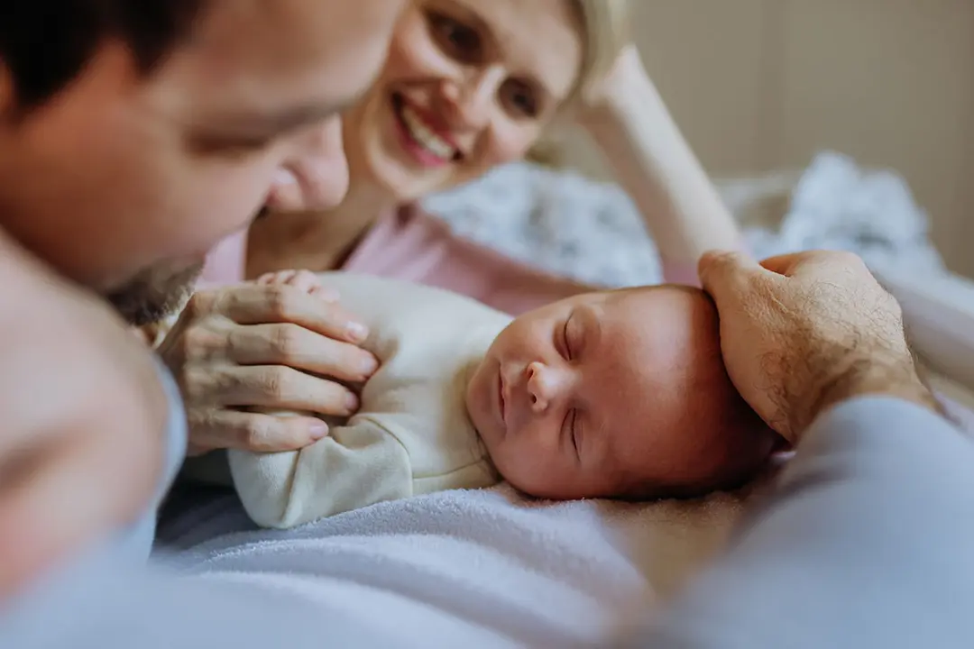 Un beb&eacute; reci&eacute;n nacido duerme mientras es velado por sus padres
