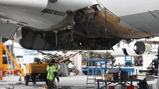 Un operario arregla la parte inferior de un avi&oacute;n