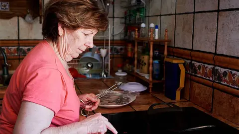 una anciana encendiendo la vitrocer&aacute;mica