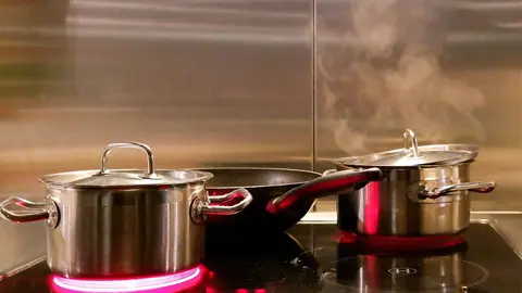 Unas ollas sobre una vitrocer&aacute;mica encendida