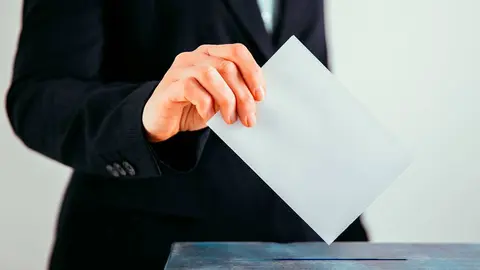 Un hombre depositando un voto en una urna