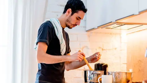Un joven con camiseta negra cocinando en casa