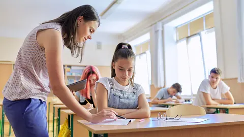 Profesora joven ense&ntilde;a lecci&oacute;n en clase de ni&ntilde;os adolescentes