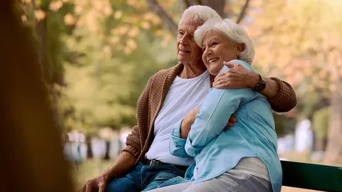 Pareja, ancianos y abrazados en el parque durante la jubilaci&oacute;n