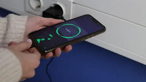 persona conectando el m&oacute;vil a la electricidad
