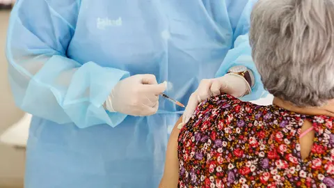 Una sanitaria inyectado una vacuna a una paciente mayor