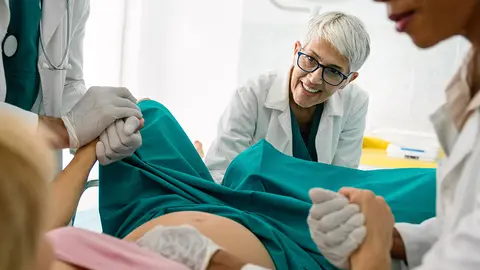 Una mujer dando a luz con profesionales a su alrededor