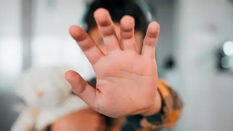 Un menor oculta su cara con la mano en un acto para esconder violencia