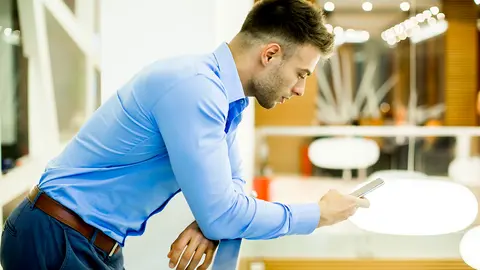 Un joven empleado revisando su tel&eacute;fono m&oacute;vil