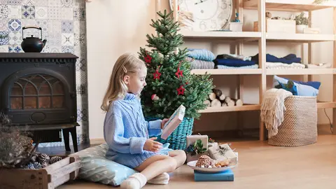 Ni&ntilde;a recibe un regalo bajo el &aacute;rbol de Navidad en casa