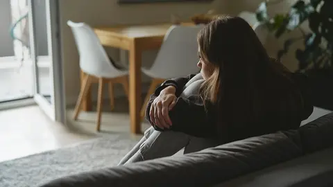 Mujer triste cauc&aacute;sica sentada en el sof&aacute; con depresi&oacute;n