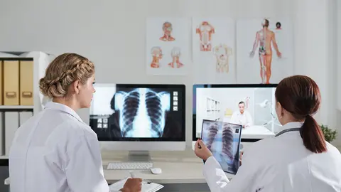 Dos m&eacute;dicos mirando unas radiograf&iacute;as de un paciente con neumon&iacute;a