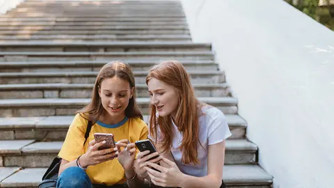 Dos adolescentes con m&oacute;viles en la mano