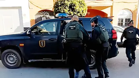 Agentes de la Guardia Civil introducen en un coche al detenido