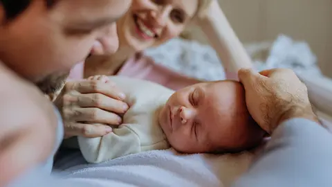 Un beb&eacute; reci&eacute;n nacido duerme mientras es velado por sus padres