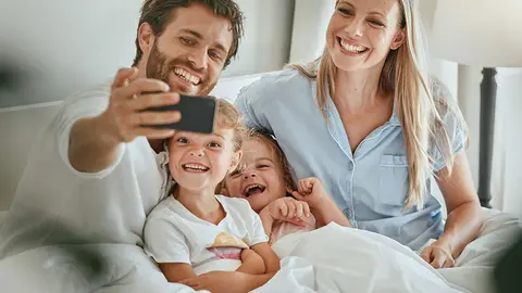 Una familia en la cama haci&eacute;ndose un selfie