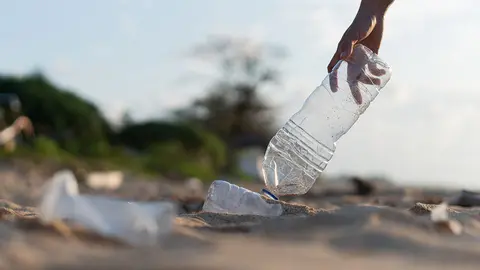 Un voluntario recogiendo pl&aacute;stico del mar