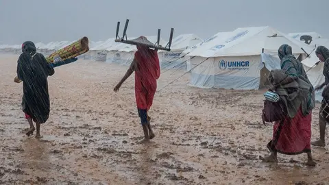 ACNUR/Aymen Alfadil Las mujeres llevan sus pertenencias a trav&eacute;s del suelo fangoso en un lugar de reuni&oacute;n para desplazados internos cerca de Kassala, Sud&aacute;n. Foto. ONU