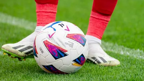Los pies de un futbolista tocan el bal&oacute;n sobre el c&eacute;sped de un estadio de f&uacute;tbol. Foto: LALIGA