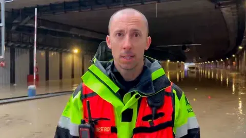 El jefe de bomberos junto al t&uacute;nel inundado. Foto: Emergencias Madrid