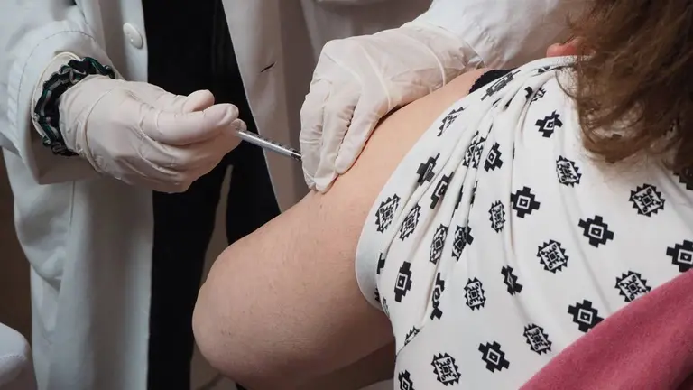 Un m&eacute;dico pone una vacuna en el brazo de una mujer
