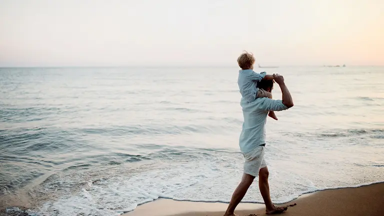 Padre con un ni&ntilde;o peque&ntilde;o caminando en la Playa en vacaciones de verano, divirti&eacute;ndose.