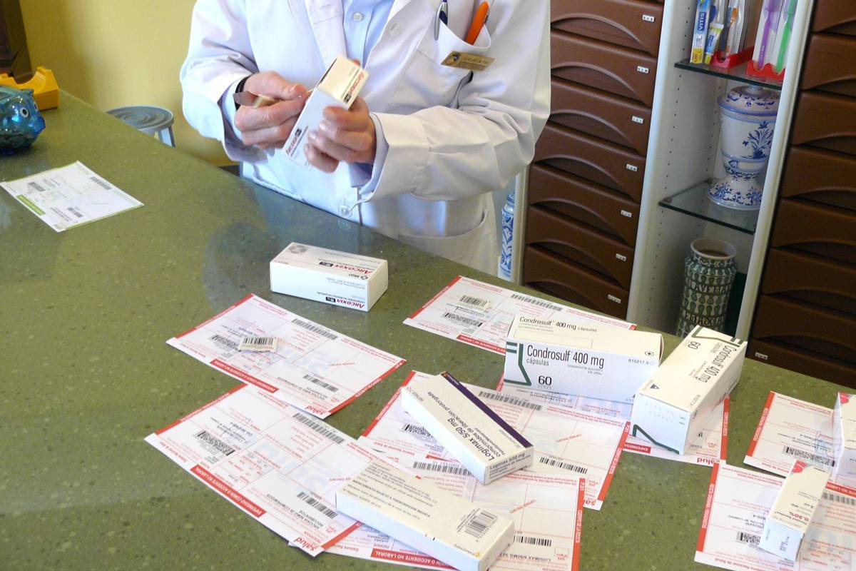 Un farmacéutico expone sobre un mostrador varios medicamentos con recetas